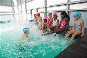 Group Of Kids Kicking Their Legs During A Swim Lesson